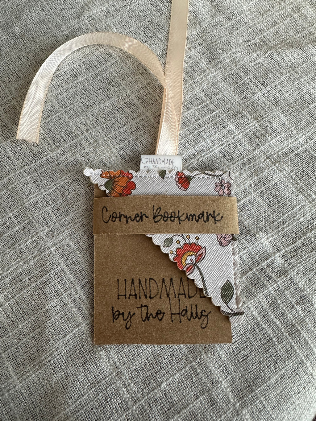 Handcrafted floral corner bookmark featuring green leafy vines and red folk blossoms on cream faux leather with a cream satin ribbon loop.⁠
